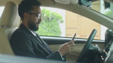 Arabada oturan ve cep telefonuyla interneti karıştıran işadamlarının yan görüntüsü