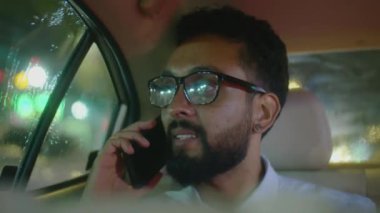 Resmi giyimli ve gözlüklü iş adamının takside konuşurken cep telefonuyla çektiği göğüs resmi.