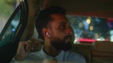 İş adamının ön koltuğundan kablosuz kulaklıklarla müzik dinlerken ve gece taksideyken pencereden bakarken görüntüyü al