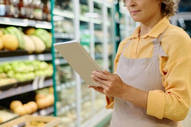 Ürünleri çevrimiçi kontrol etmek için tablet pc kullanan süpermarket yöneticisi