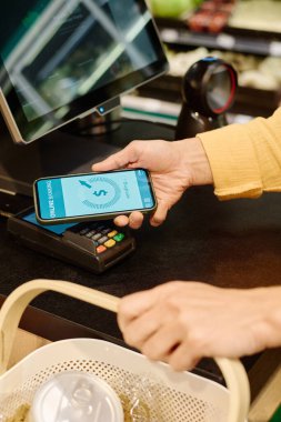 Süpermarkette akıllı telefonla ödeme yapan müşterilerin dikey görüntüsü