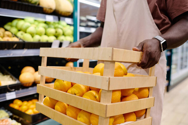 Close-up of African American store worker carrying fresh fruits for sale in supermarket