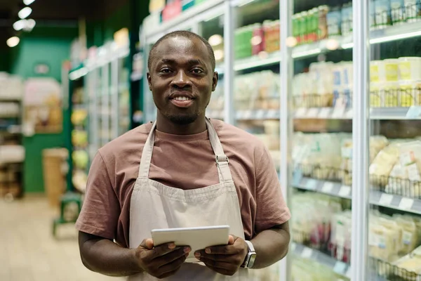 Tablet bilgisayarla işi kontrol ederken kameraya gülümseyen Afrikalı Amerikalı süpermarket çalışanının portresi