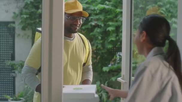 快乐的男性信使把披萨盒送给女性顾客 在家里送餐时与她交谈 — 图库视频影像