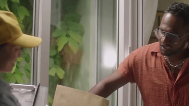 Fiatal Fekete Férfi Nyitja Ajtót Vesz Csomagot Női Futár Beszél — Stock videók
