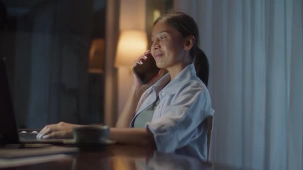 Femeie Asiatică Care Vorbește Telefonul Mobil Folosește Laptopul Timp Lucrează — Videoclip de stoc