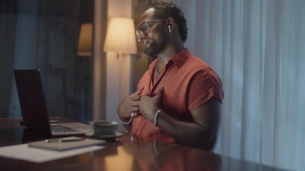 在家里过夜的时候 用无线耳机通过笔记本电脑上的视频通话 拍下了一个快乐的黑人男子的中景照片 — 图库视频影像