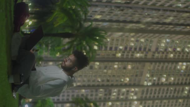 Вертикальный Снимок Молодого Человека Толстовке Сидящего Рюкзаком Траве Городском Парке — стоковое видео