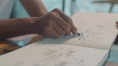 Albümde resim çizen Asyalı genç adamın, resim stüdyosundaki masasında mum pastel boya ile yakın çekim.