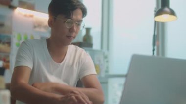 Genç Asyalı tasarımcının gündelik kıyafet ve gözlük giyip sanat stüdyosunun masasında çalışırken seçmeli odak fotoğrafı.