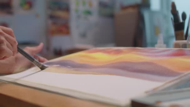スタジオで紙に抽象的な絵を描いている間 ペンキを紙に塗るアジアの男性アーティストのクローズアップショット — ストック動画