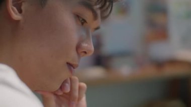 Genç Asyalı ressamın resim stüdyosunda yeni bir resim üzerinde çalışırken fırçadan fazla boya sallamasını yakın çekim yapın.