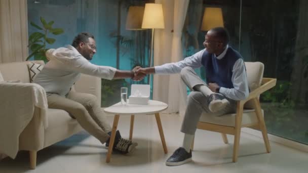 完整拍摄的男性患者握手问候非洲裔美国心理学家 并在晚上与他进行咨询 — 图库视频影像