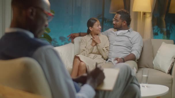 在心理治疗期间 一对快乐的夫妻坐在沙发上 一边与心理医生拥抱和交谈一边做笔记的选择性聚焦镜头 — 图库视频影像