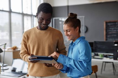Genç meslektaşlar bilişim bürosunda takım çalışması sırasında tablet bilgisayar kullanıyorlar
