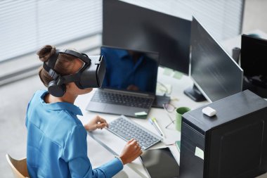 Bilgi işlem ofisinde VR gözlüklerini test eden genç bir kadının yüksek açılı görüntüsü