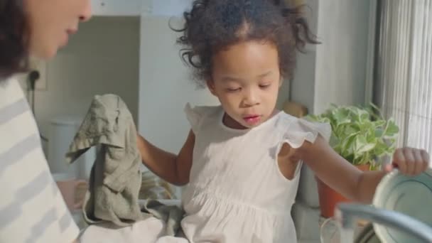 Очаровательная Азиатская Малышка Сидит Кухонном Столе Держит Полотенце Тарелкой Помогая — стоковое видео