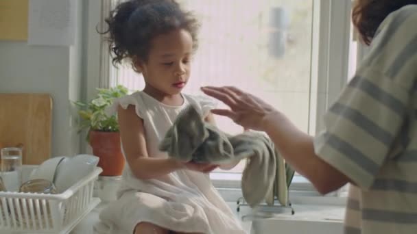 キッチンカウンターに座っているアジアの幼い少女と自宅で料理をする方法を学んでいる間 ママの助けを借りてタオルで乾燥プレート — ストック動画