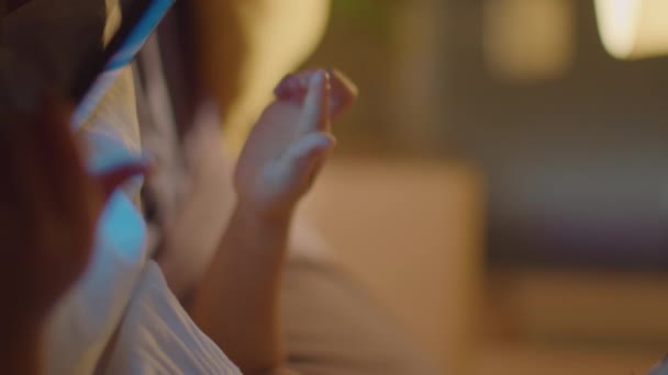 一个情绪激动的亚洲小女孩晚上在家里坐着 一边玩着数码平板电脑 一边笑 一边兴奋 — 图库视频影像