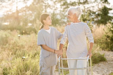 Hemşire yaşlı bir kadınla dışarı çıkıyor, Walker ve hemşireyle yürüyor ve ona yardım ediyor.