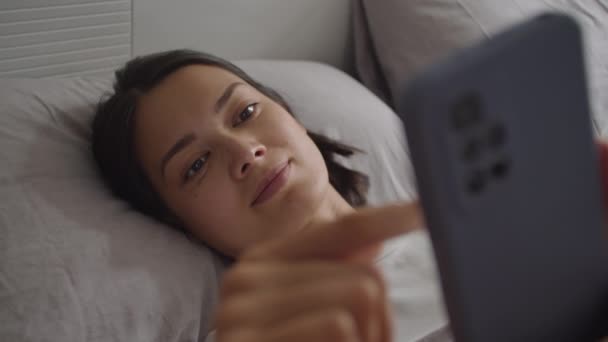 Молодая Женщина Лежит Постели Просматривает Социальные Сети Телефону После Пробуждения — стоковое видео