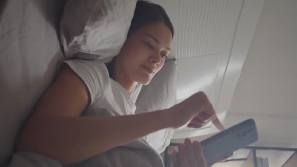 Vertical Shot Young Woman Lying Bed Scrolling Social Media Smartphone — Stock Video