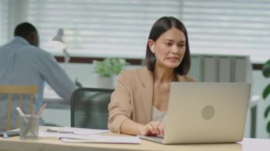 Formalite ve kablosuz kulaklık takmış güzel bir iş kadınının ofiste çalışırken internet üzerinden konuştuğu orta boy bir fotoğraf.