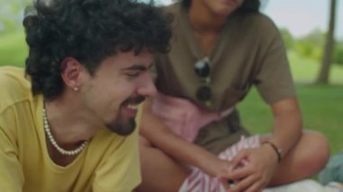 Genç arkadaşların parkta çimenlikte dinlenirken, piknik yaparken ve yaz boyunca dışarıda dijital tablette sosyal medyayı tartışırken orta derecede yakın çekim.