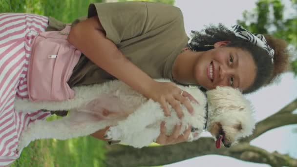 Tiro Vertical Chica Alegre Sonriendo Cámara Sosteniendo Lindo Perro Mientras — Vídeos de Stock