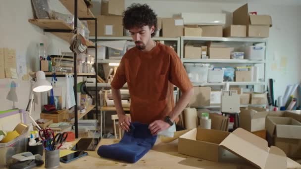 Młody Pracownik Pakujący Ubrania Tekturowego Pudełka Podczas Przygotowywania Zamówienia Wysyłkę — Wideo stockowe