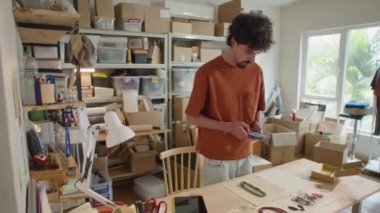 Piyasada internet üzerinden satılmak üzere cep telefonuyla son moda mücevherlerin fotoğraflarını çeken genç adamın orta boy fotoğrafı.