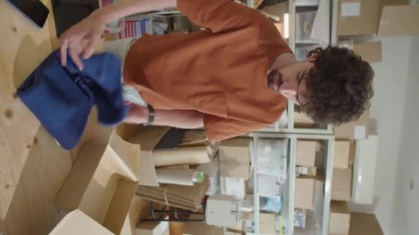 Vertical Shot Young Man Packing Garment Cardboard Parcel Box While — Stock Video