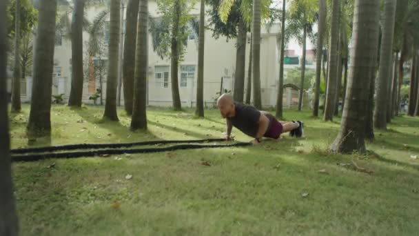 夏日外出锻炼时 身穿运动服的强壮男子在公园绿草上做拉绳动作 动作缓慢 — 图库视频影像