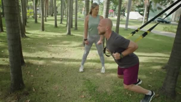 在公园里与私人女教练一起进行户外运动时 穿着运动服 头戴吊带的男子全镜头 — 图库视频影像