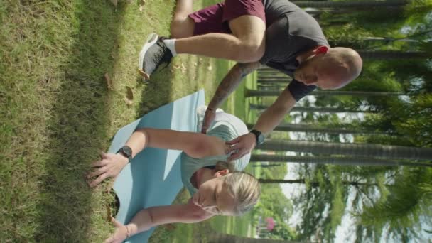 男子健身教练向公园室外锻炼时在垫子上做踏板的年轻女运动员解释运动的垂直照片 — 图库视频影像