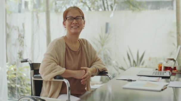 Senior Asiatisk Kvinna Sitter Rullstol Vid Skrivbord Hemmakontoret Poserar Kamera — Stockvideo
