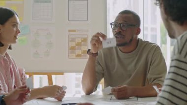 Afrikalı Amerikalı erkek öğretmen İngilizce dersi sırasında kelime kartları gösteriyor ve bunları yetişkin göçmen öğrencilere anlatıyor.