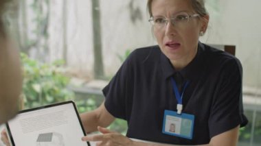 Kadın mühendisin dijital tablet üzerindeki yenilenebilir enerji projesini, ofiste yaptığı toplantıda erkek arkadaşa açıkladığı omuz üstünden.