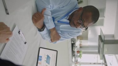 Ofisteki iş görüşmesi sırasında tablet üzerinde fotovoltaik sistem projesini tanımlayan Afrikalı Amerikalı erkek mühendisin omuz üstü fotoğrafı.