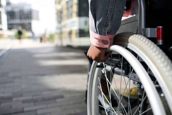 Крупный план женщины с ограниченными возможностями, движущейся в инвалидной коляске вдоль улицы