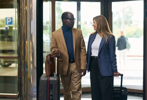 Multiethnic business couple with luggage entering the hotel for check in
