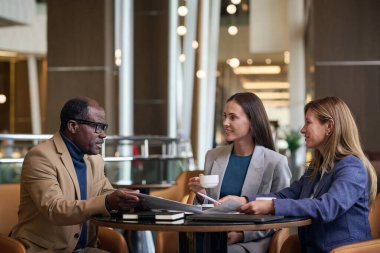 İş arkadaşları otelde toplanıyor, masada oturuyor ve ekip halinde çalışma anlarını tartışıyorlar.