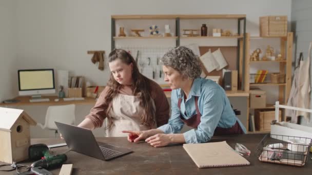 ダウン症の女の子とノートパソコンを使用して中年の女性教師 木工研修会で話し — ストック動画