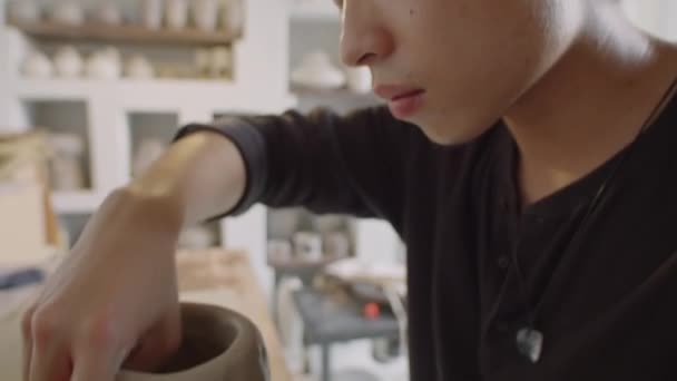 车间用陶瓷轮上的粘土做花瓶的亚洲年轻陶工倒立拍摄 — 图库视频影像