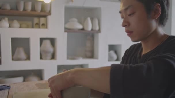 亚洲年轻陶工在陶瓷工作室工作时用砂轮在泥土中形成花瓶的倒立镜头 — 图库视频影像
