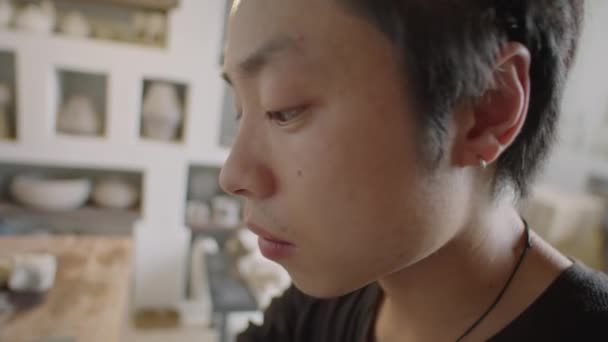 Çalışırken Genç Asyalı Çömlekçinin Seramik Bardağa Tutamağı Takarken Çekilen Yatay — Stok video