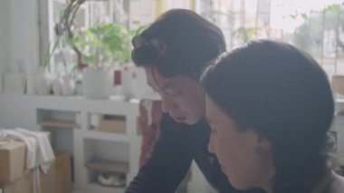 Erkek çömlek öğretmeni, sanat stüdyosunda seramik dersinde kadın öğrencilere kille nasıl çalışacaklarını gösteriyor.