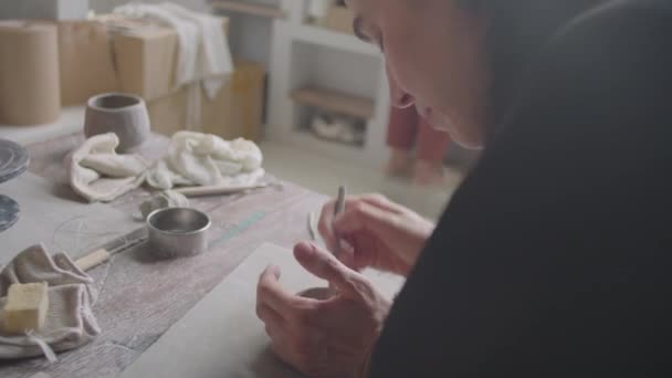 職人のスタジオで陶芸教室をとりながら陶器具で粘土を形作る若い女性のハンドヘルドカメラショット — ストック動画