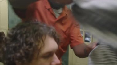 Profesyonel siyah berber erkek müşteriye çizgili kuaför pelerini giydirip saçını kestirmeye hazırlanıyor.