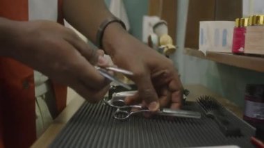Berber dükkanında çalışma aletlerini hazırlarken makas takan erkek berberin kırpılmış elleri.